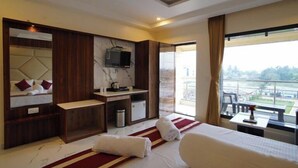 A hotel room with a bed, a desk, a TV, and a view of the outdoors. - Lipi Resort and Spa (Kanthi)