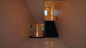 A staircase with a handrail leading to a landing. The walls are plain with a light color, and the floor is tiled. - Lipi Resort and Spa (Kanthi)