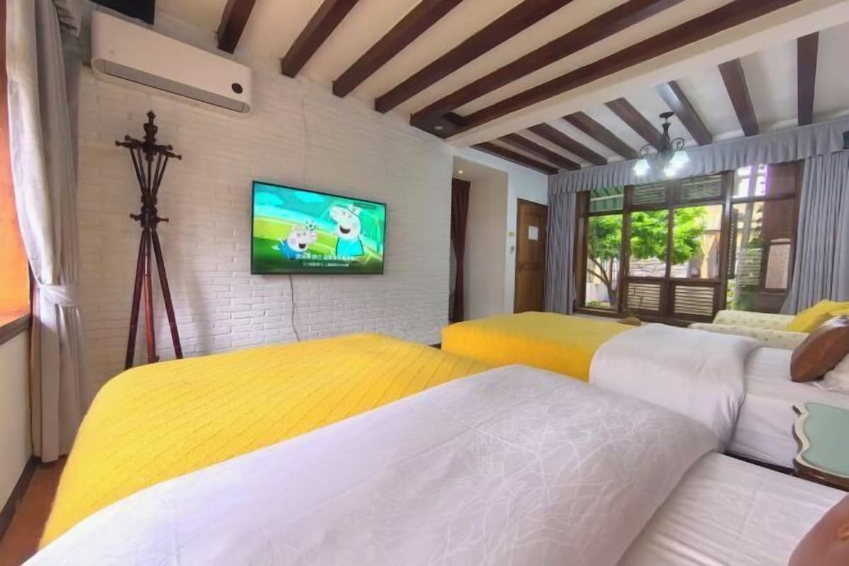 Habitación de hotel con dos camas, un televisor en la pared y una ventana con cortinas.