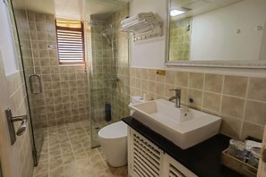 A bathroom with a glass-enclosed shower, a sink, and a toilet.