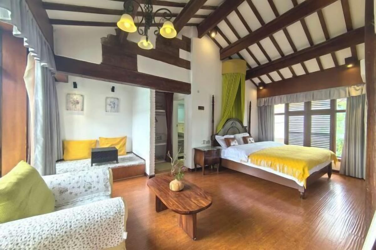 Un dormitorio con una cama de madera, un sofá, una mesa de centro de madera y un escritorio.