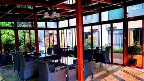 An outdoor seating area with wicker furniture and red pillars. - Junchen Business Hotel (Chongqing)