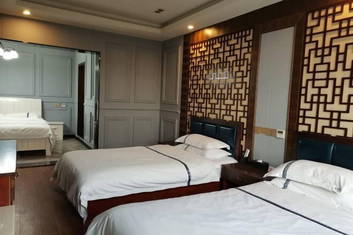 A hotel room with two beds, a wooden headboard, a mirror, and a decorative wall panel.