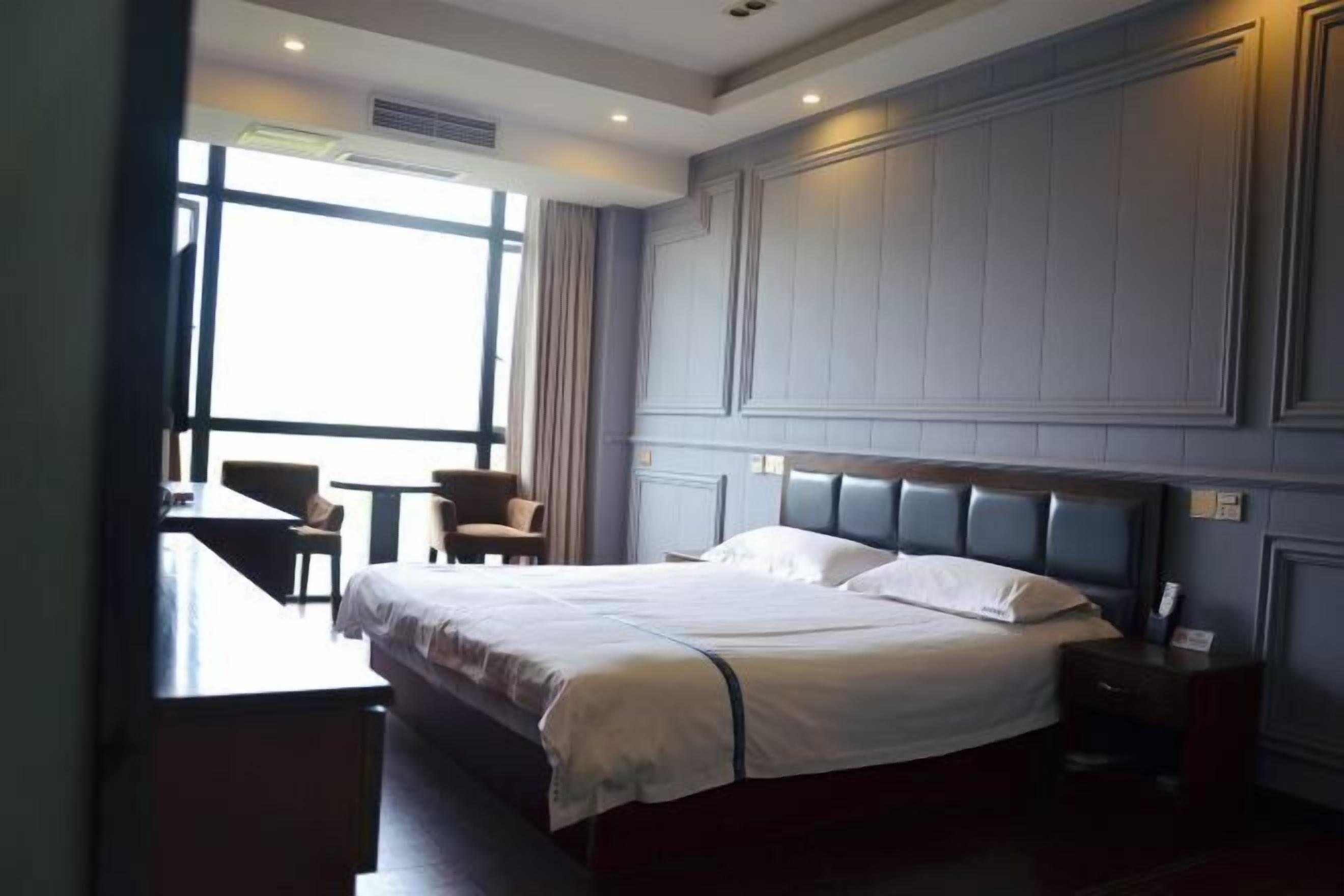 A hotel room with a large bed, a desk, and a chair.