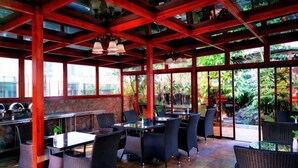 An outdoor restaurant with tables and chairs, a red ceiling, and large windows. - Junchen Business Hotel (Chongqing)