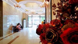A hotel lobby with chandeliers, a reception desk, and a large floral arrangement. - Junchen Business Hotel (Chongqing)