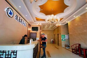A hotel reception area with a reception desk, a chandelier, and a sign with Chinese characters. - Junchen Business Hotel (Chongqing)