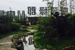 Um jardim com lago, trilha e plantas de bambu.