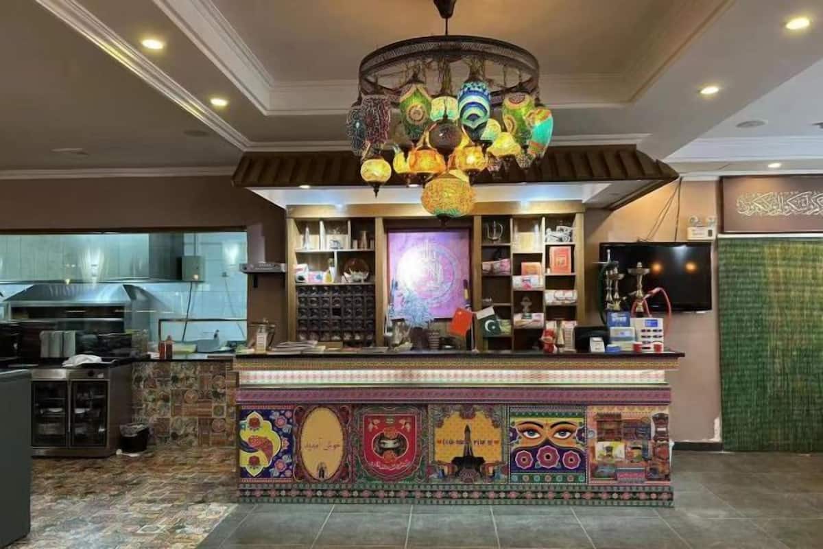 Un restaurant doté d’un comptoir aux couleurs vives et aux motifs originaux, ainsi que de différents types de luminaires décoratifs suspendus.
