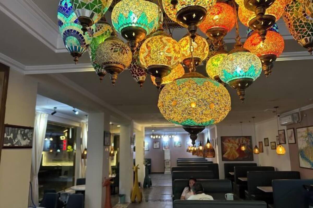 Un restaurant décoré de lampes suspendues élégantes et doté d’un espace où sont disposées des tables et des chaises.