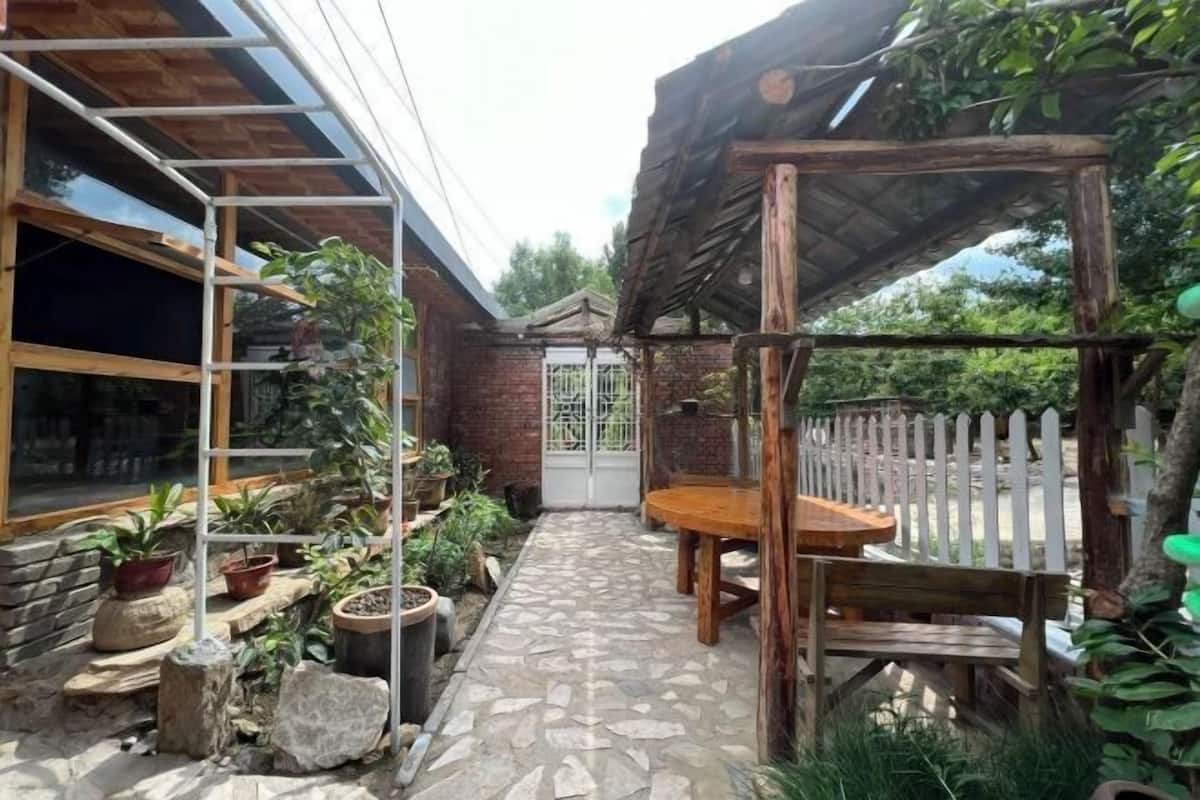 Une terrasse avec un chemin en pierre, des meubles en bois et des plantes en pot.