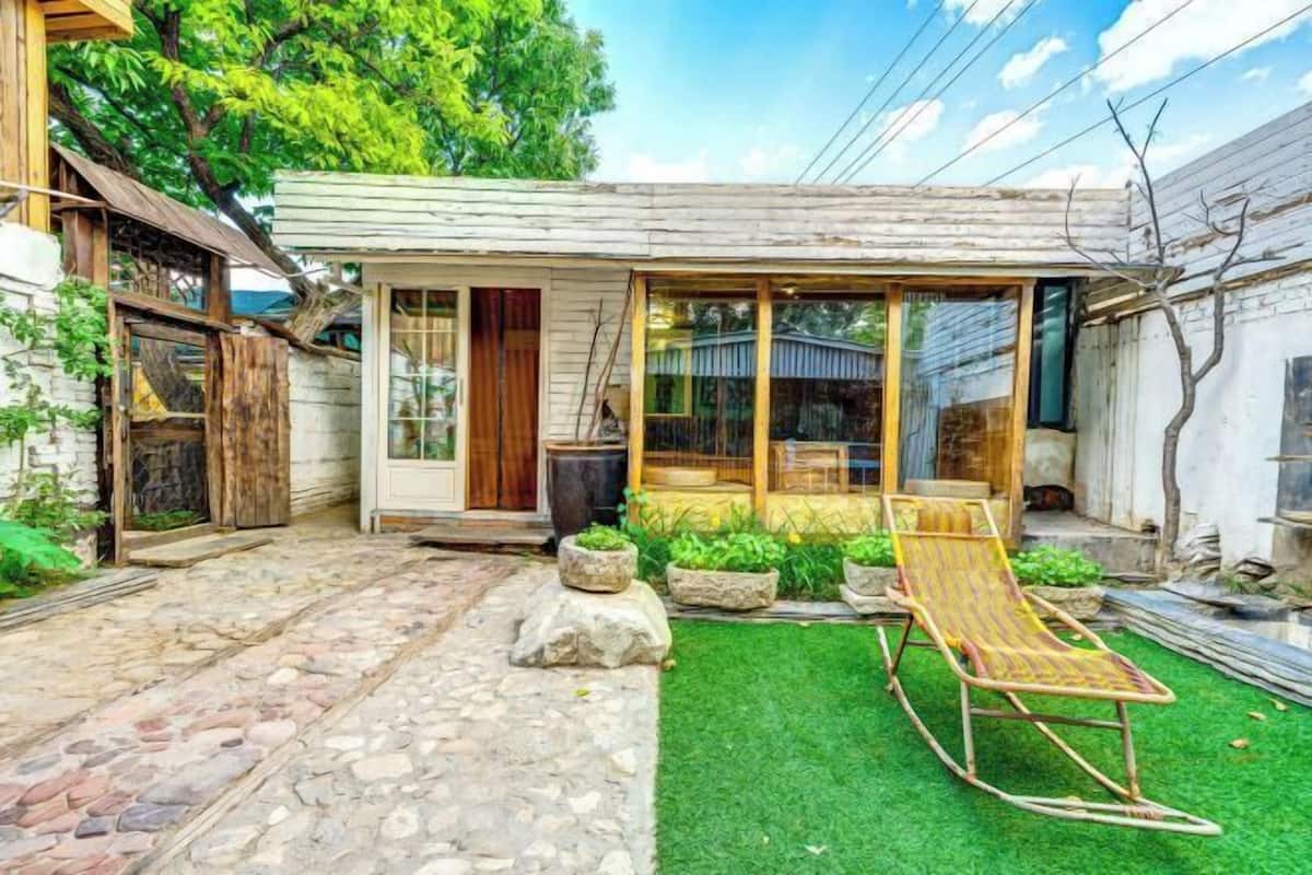 Une maison de campagne, avec un chemin de pierre, une pelouse verdoyante et une balançoire en bois.