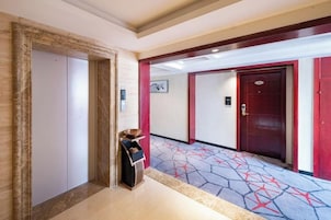 Un pasillo de hotel con alfombra estampada, un guardarropa y una puerta de marco rojo.