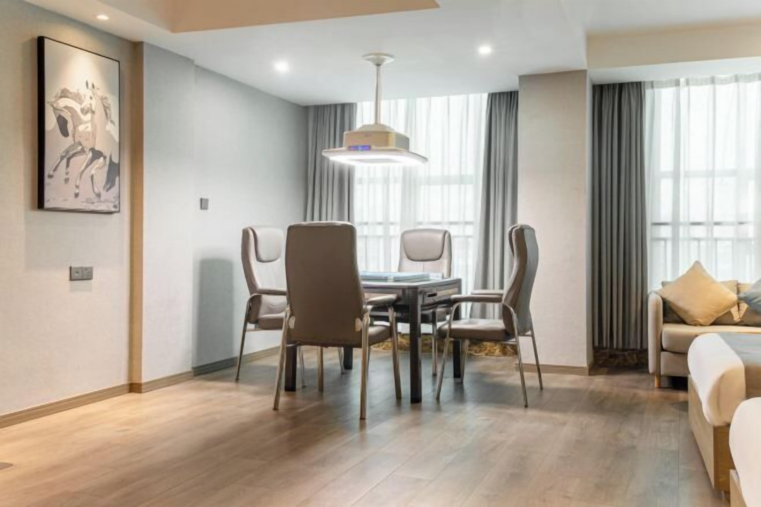 A modern hotel room with a dining area, a sofa, and a large window.