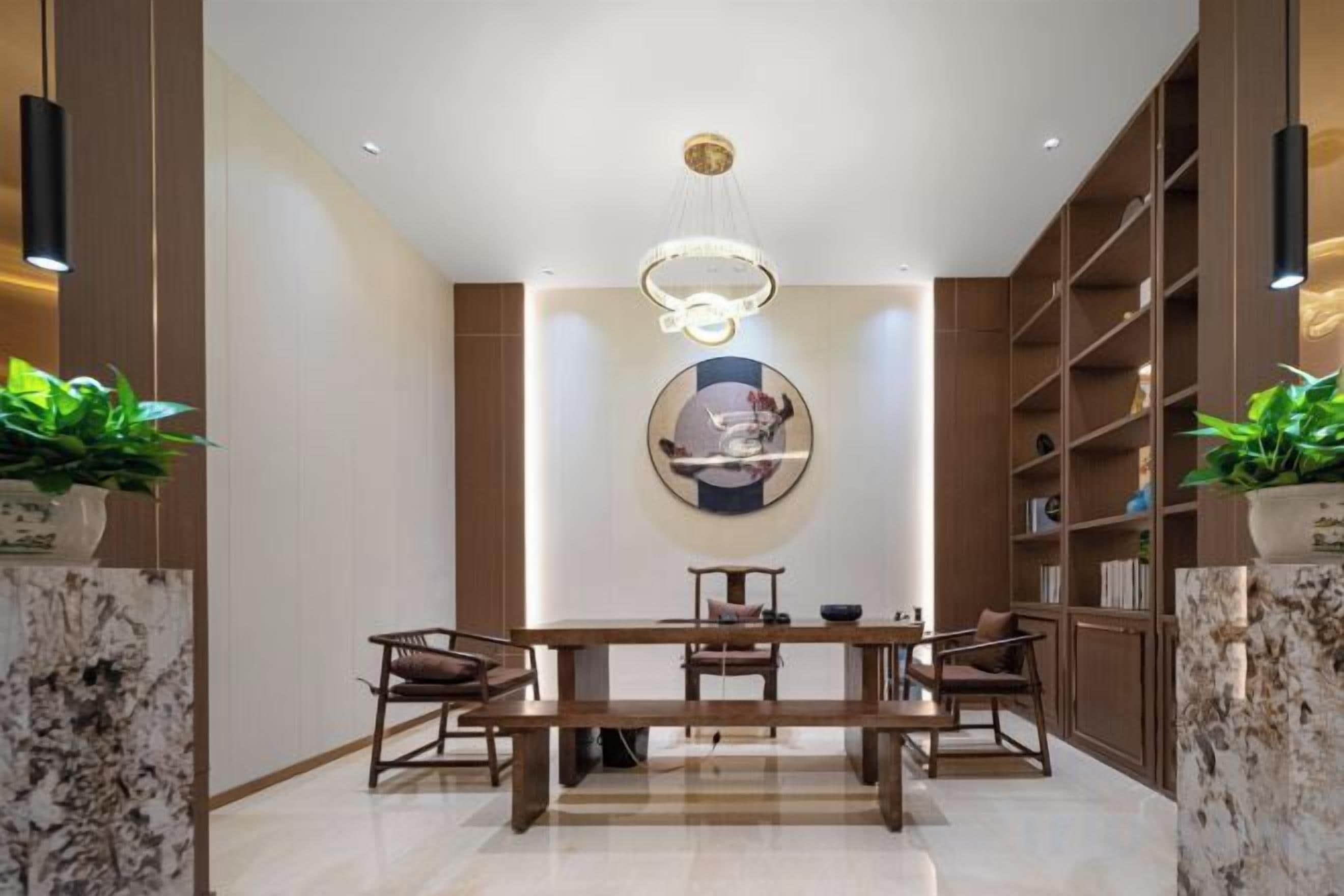 Un comedor moderno con encimera de mármol, una mesa de madera y sillas. Se aprecia una gran obra de arte circular en la pared y una estantería a la derecha.