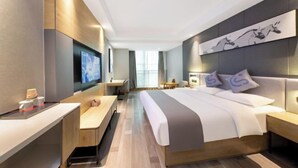 A modern hotel room with a large bed, a desk, a flat-screen TV, and a wall-mounted artwork. - Yayue Hotel (Yongxin Central Plaza) (Yongxin)