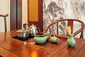 A wooden dining table with green teapots, a kettle, and a vase with chopsticks. - Yayue Hotel (Yongxin Central Plaza) (Yongxin)