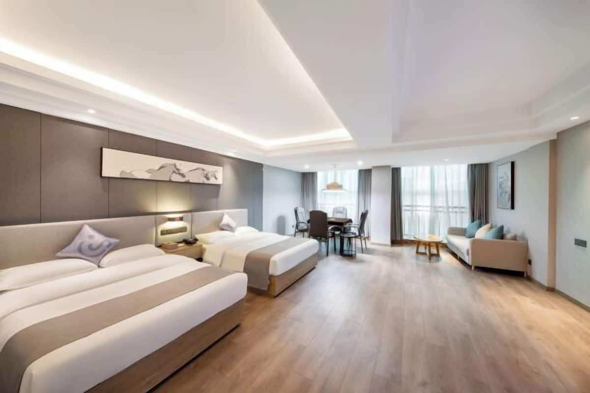 A hotel room with two beds, a desk, and a sofa.