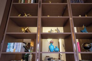 A bookshelf with multiple shelves, some containing books and others with decorative items like vases and figurines. - Yayue Hotel (Yongxin Central Plaza) (Yongxin)