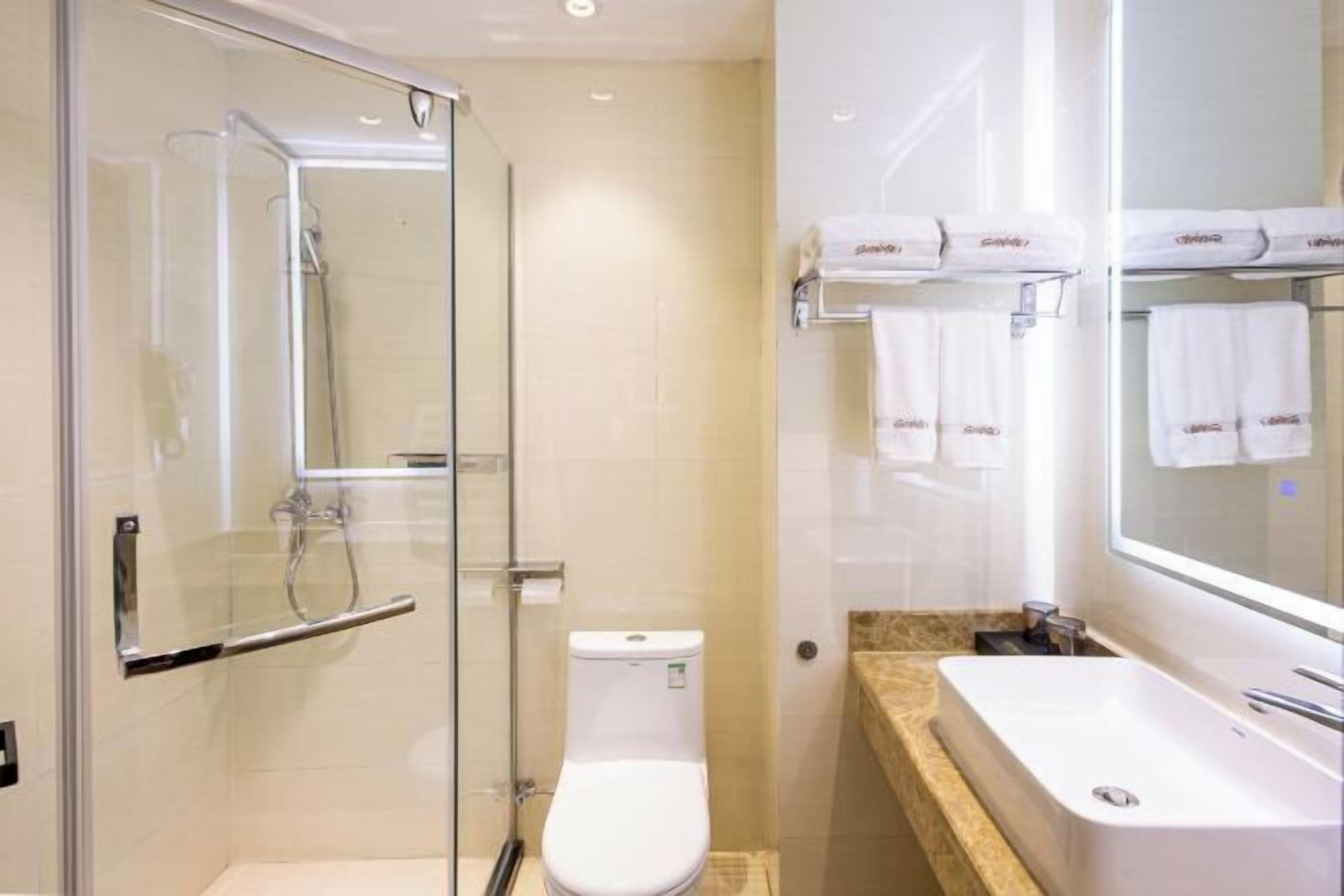 A modern bathroom with a glass-enclosed shower, a white toilet, and a sink with a mirror above it.