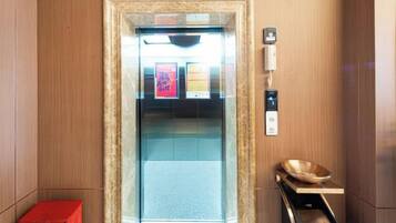 An elevator with a marble frame, a red box, and a wooden tray with a bowl.