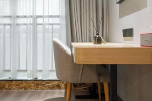 A modern room with a wooden desk, a chair, a window with curtains, and a wall-mounted switch. - Yayue Hotel (Yongxin Central Plaza) (Yongxin)