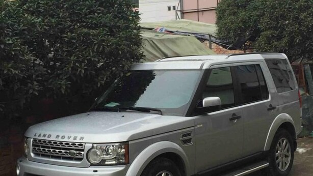 Un SUV Land Rover plateado estacionado en una entrada de casa.