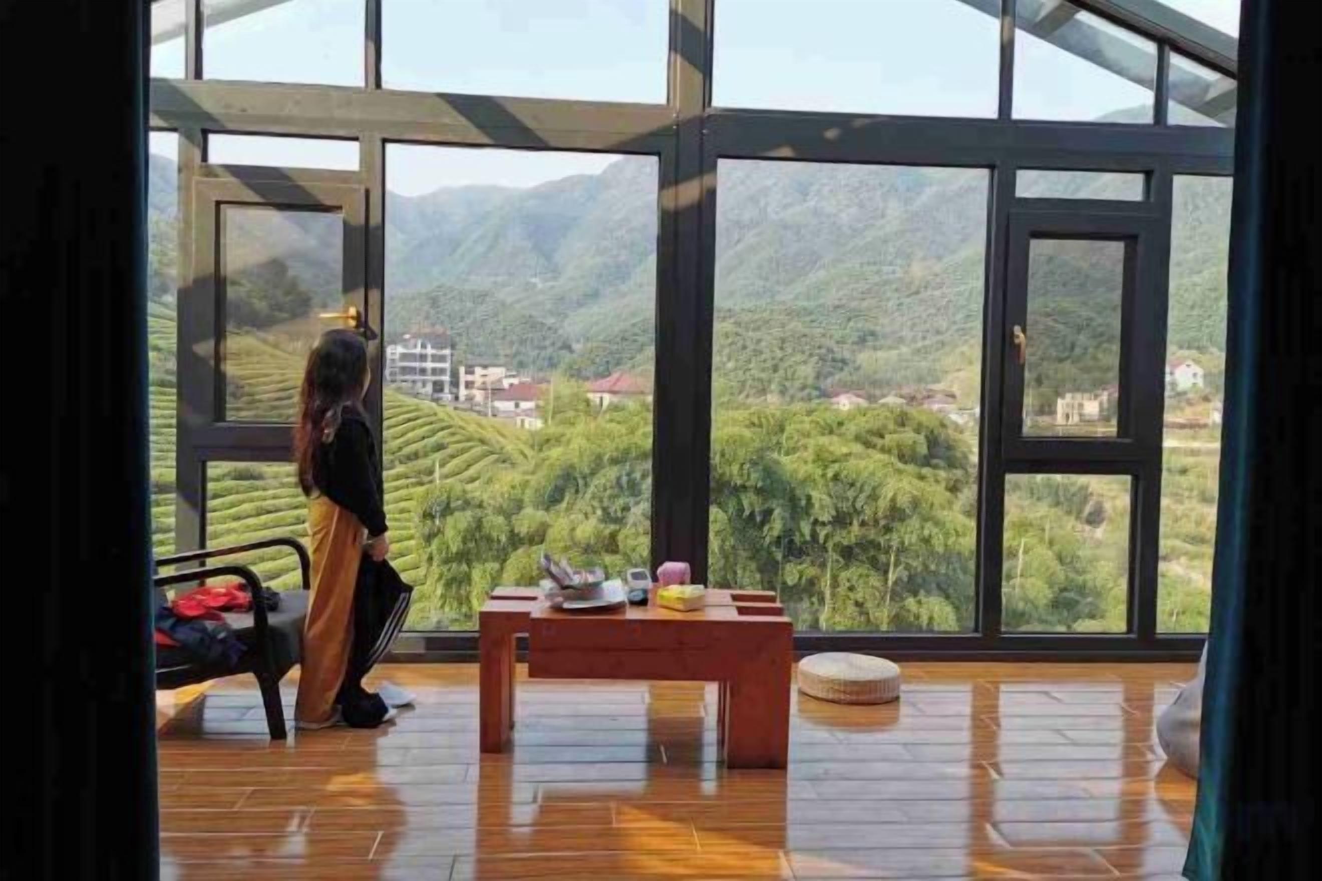 A room with large windows, a wooden floor, and a table with items on it.