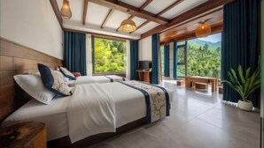 Une chambre avec deux lits, un plafond en bois, une grande fenêtre donnant sur un beau paysage et un balcon.