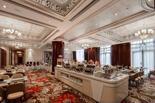 Un comedor de hotel con una barra libre, un amplio suelo alfombrado y un candelabro.
