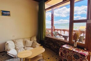 Relax in a cozy room with a large window offering a view of the outdoor terrace and seating area.