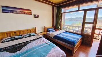 Habitación con dos camas, un cuadro en la pared y vistas a montañas a través de amplias ventanas.