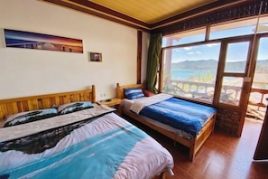 A room with two beds, a painting on the wall, and a view of mountains through large windows. - Xingkong Inn (Yanyuan)