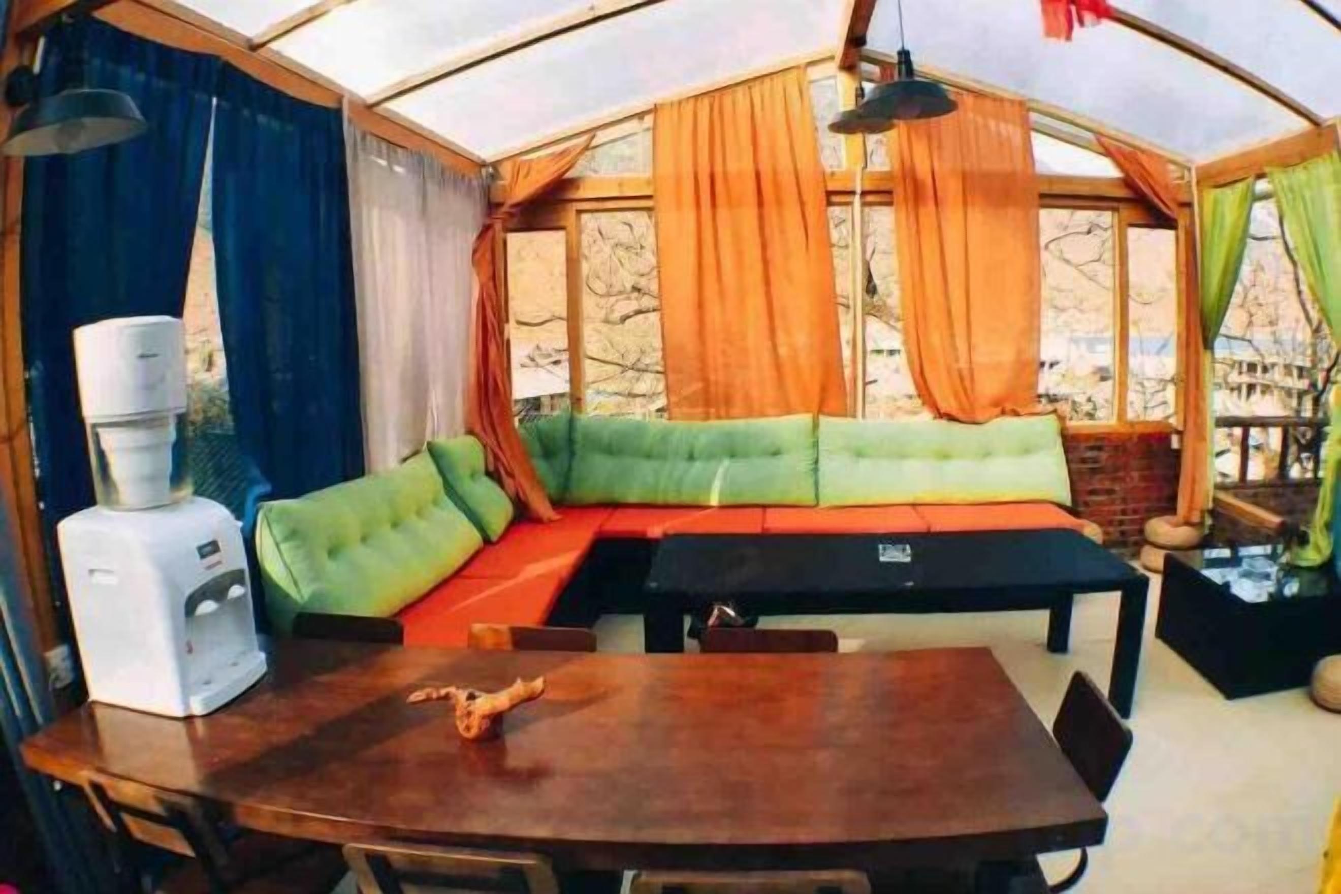 Una habitación tipo tienda de campaña con una mesa de comedor, un sofá y un dispensador de agua.