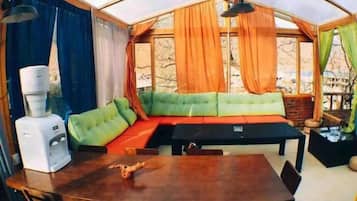 Una habitación tipo tienda de campaña con una mesa de comedor, un sofá y un dispensador de agua.