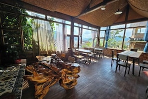 Enjoy meals in a warm and inviting dining area with high ceilings, exposed beams, and large windows offering views of the surrounding landscape.