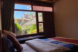 A room with a bed, a window with a view of a traditional building, and a curtain. - Xingkong Inn (Yanyuan)