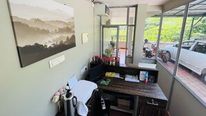 A reception desk with a view of parked cars and greenery outside. - Seven Malai Residency (Devikolam)