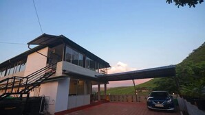 A modern two-story building with a covered driveway and a parked car. - Seven Malai Residency (Devikolam)