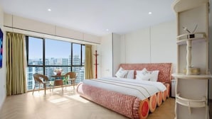 Een moderne slaapkamer met een groot bed, een eettafel, stoelen en uitzicht op de stad.