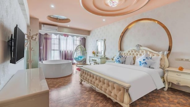 Een slaapkamer met een groot bed, een kaptafel, een badkuip en een plafond met ronde lampen.