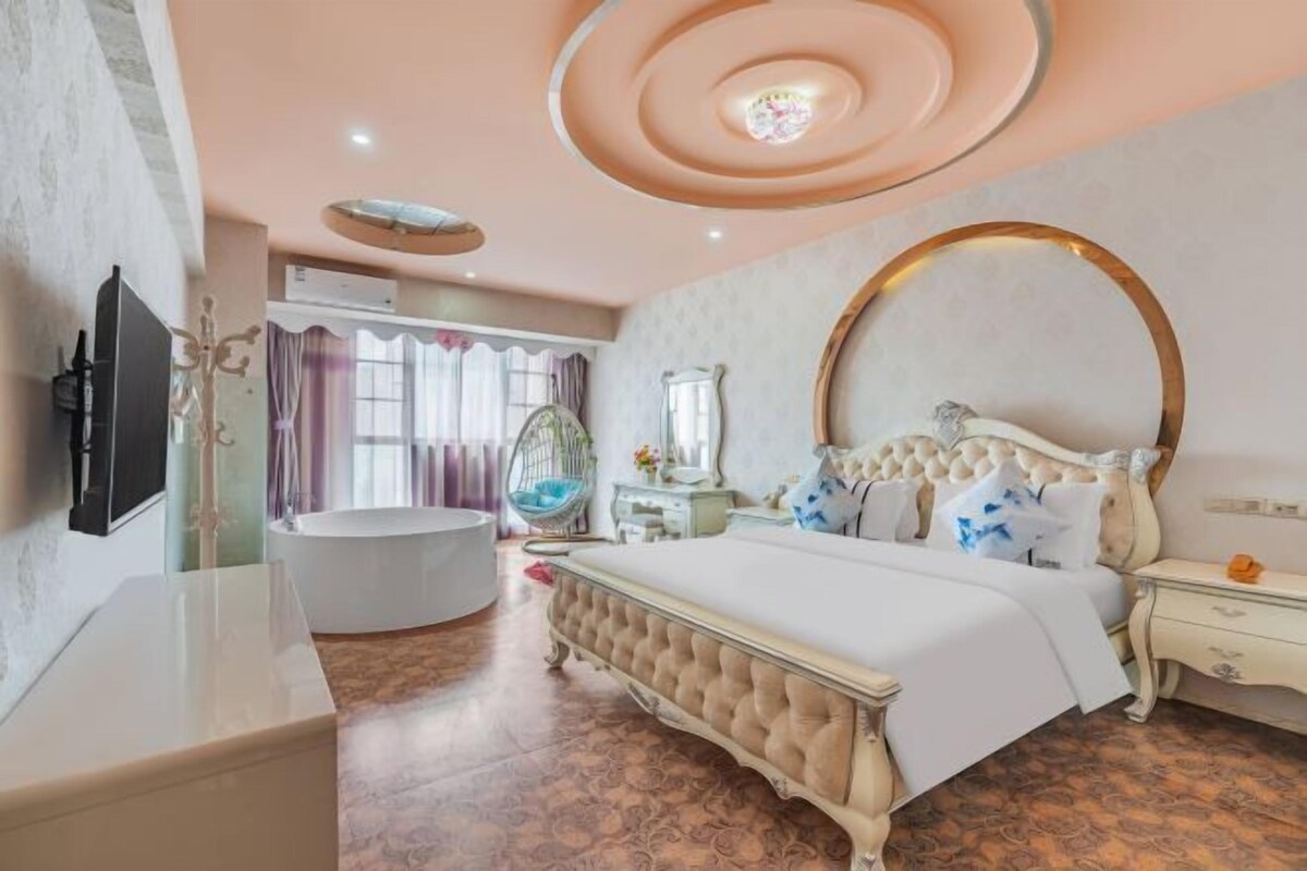 Ein Schlafzimmer mit einem großen Bett, einem Schminktisch, einer Badewanne und einer Decke mit runden Leuchten.