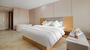 Een moderne hotelkamer met een groot bed, nachtkastjes, een zithoekje en een badkamer.