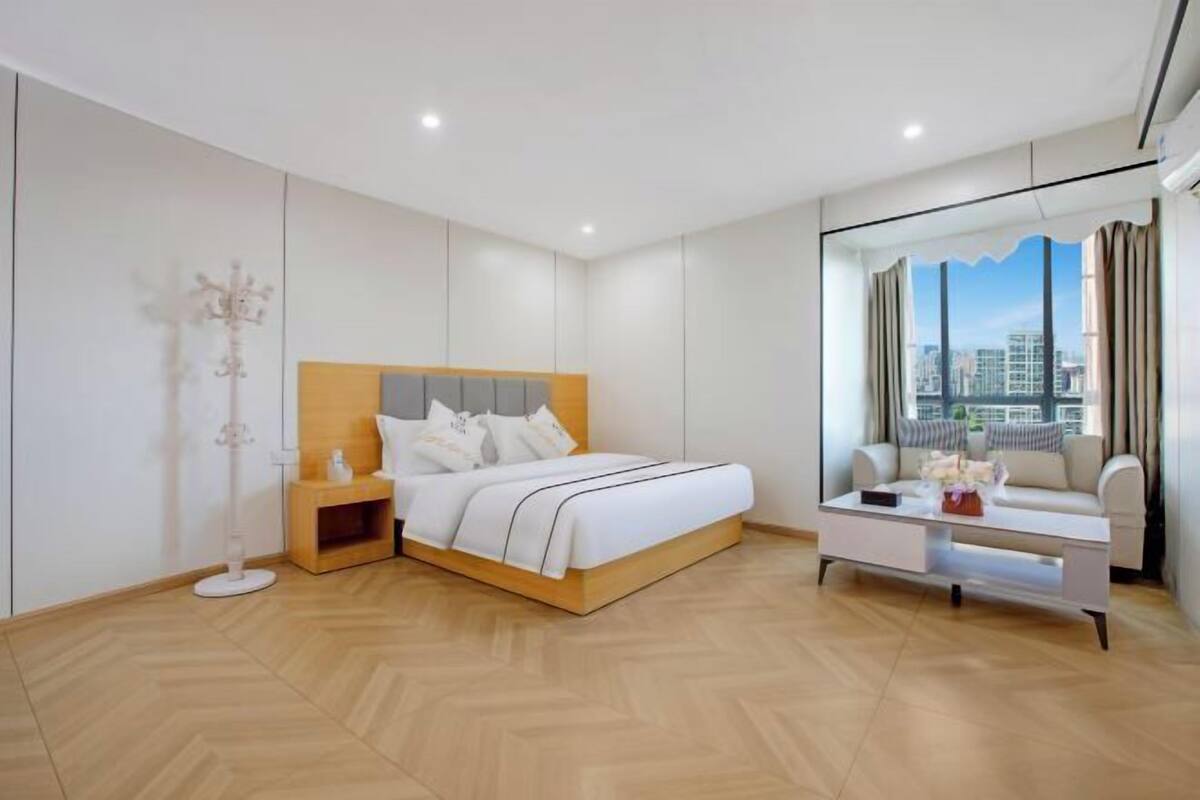 Een moderne slaapkamer met een bed, nachtkastje en uitzicht op de stad door een raam.