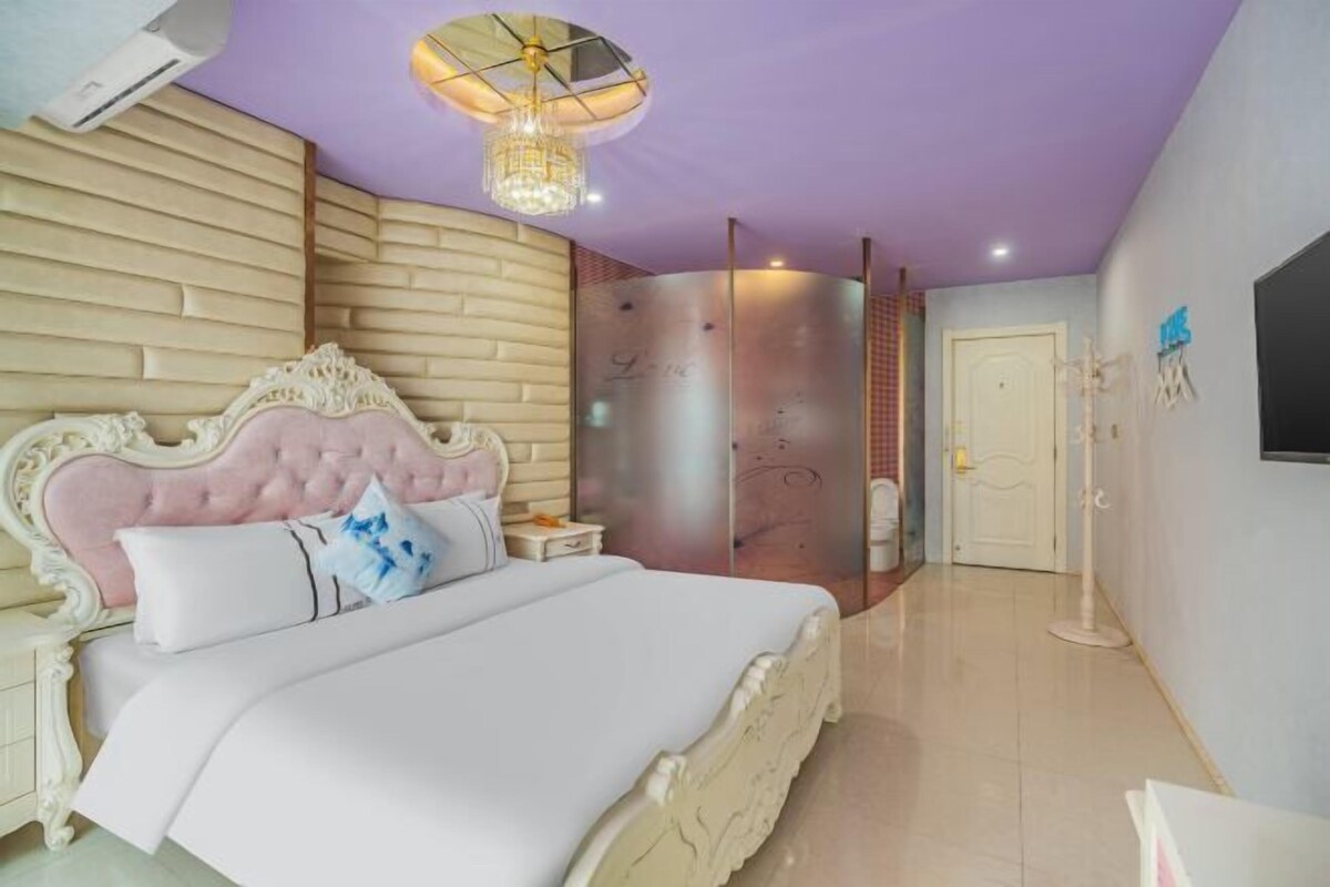 Ein Schlafzimmer mit einem großen Bett, einer Chandelüster, einem Kleiderschrank und einem an der Wand befestigten Fernseher.