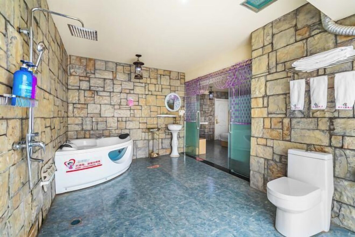 Ein Badezimmer mit Steinwand, einer Badewanne, einer Toilette und einer Duschkabine.