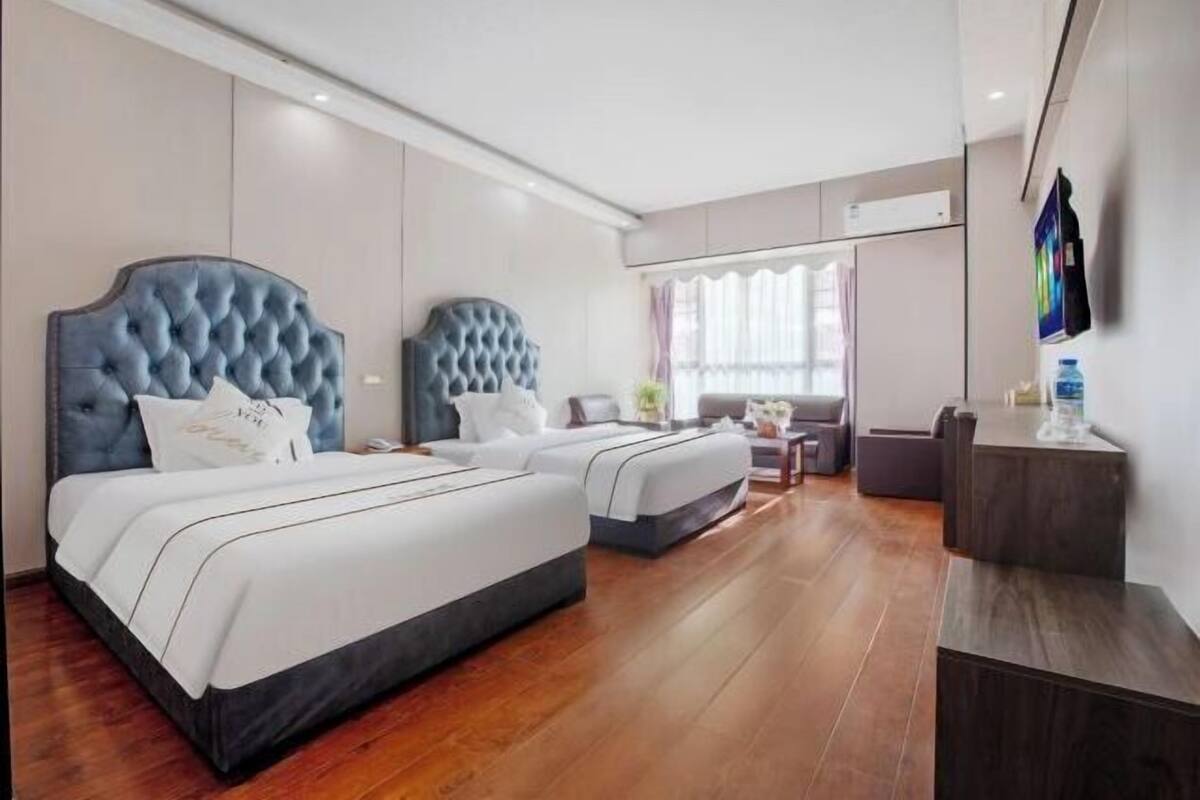 Een hotelkamer met een groot bed, een kleiner bed, een bureau en een televisie.