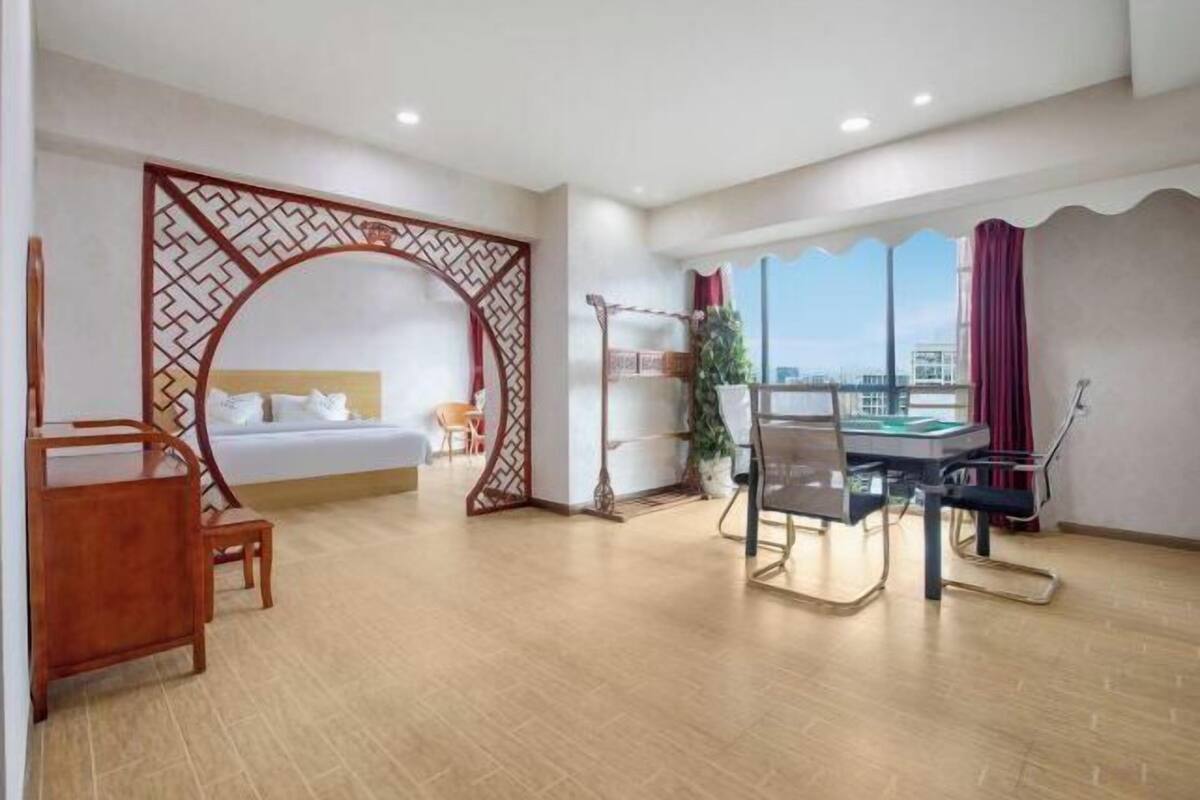 Een hotelkamer met een bed, een bureau met stoel, een balkon met uitzicht en een decoratieve scheidingswand.