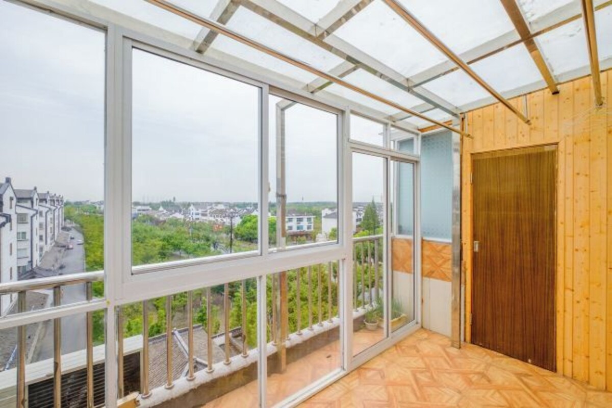 A room with large windows, a wooden door, and a view of a residential area.
