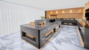 A modern kitchen with a marble countertop, wooden cabinets, and a built-in oven.